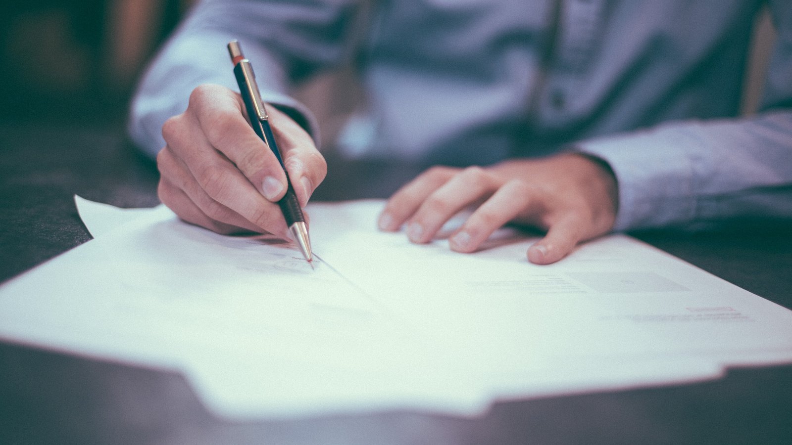 Hand signing business documents at a desk